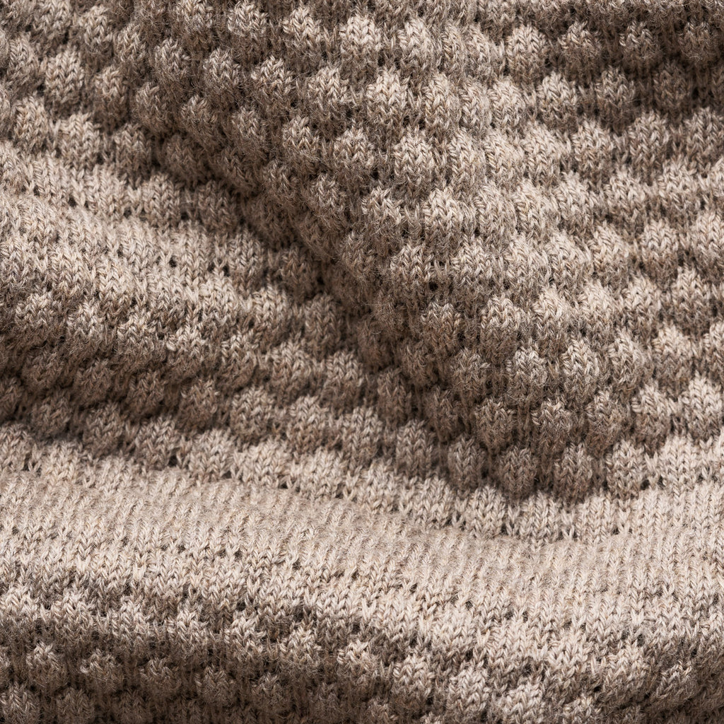 Close-up of a knitted textile with a textured honeycomb pattern in taupe and beige tones, showing the fabric weave and ribbed border. Eton Knitwear available at Sakks Menswear in Southampton.