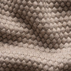 Close-up of a knitted textile with a textured honeycomb pattern in taupe and beige tones, showing the fabric weave and ribbed border. Eton Knitwear available at Sakks Menswear in Southampton.