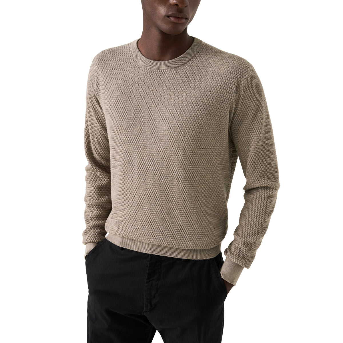 A man wearing a textured knit crewneck sweater in a light taupe-beige color, paired with black pants, against a plain white background. Eton Knitwear available at Sakks Menswear in Southampton.