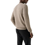 A man wearing a textured beige knit sweater and black trousers, shown from a side-back angle against a plain white background. Eton Knitwear available at Sakks Menswear in Southampton.