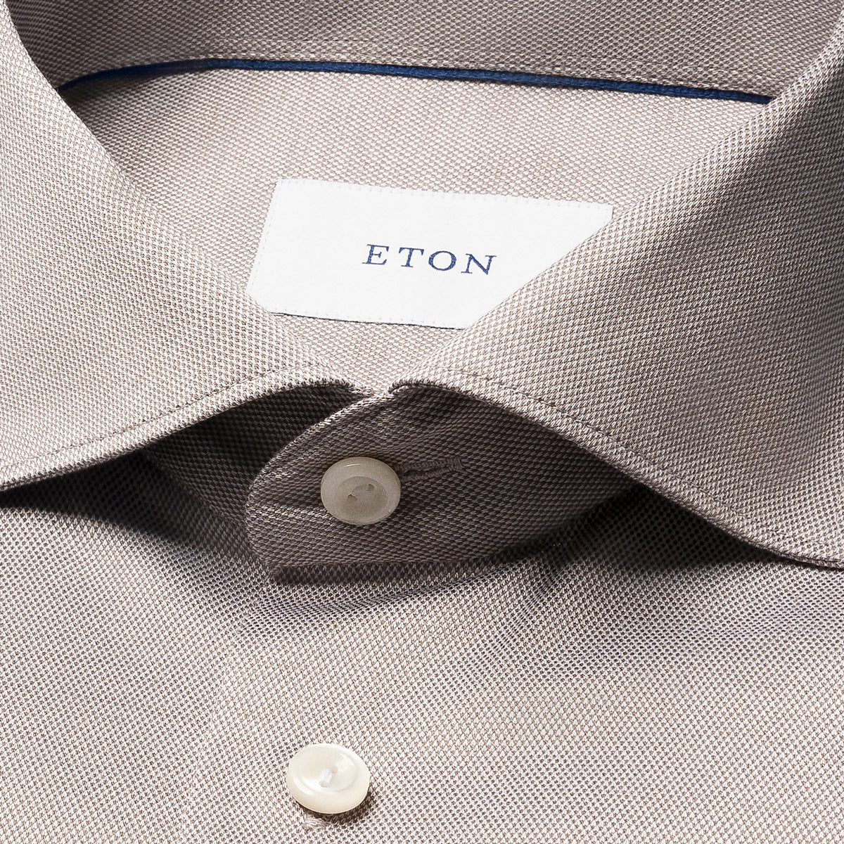 Close-up of a light grey micro-check dress shirt with a white collar label reading ETON and white buttons. Eton Shirt available at Sakks Menswear in Southampton.