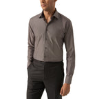 A man wearing a long-sleeve button-down dress shirt in a solid dark grey colour, paired with black trousers, shown from the chin down against a plain white background. Eton Shirt available at Sakks Menswear in Southampton.