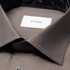 Close-up of a collared dress shirt in a taupe-grey colour, showing the inner neck label with the brand name ETON. Eton Shirt available at Sakks Menswear in Southampton.