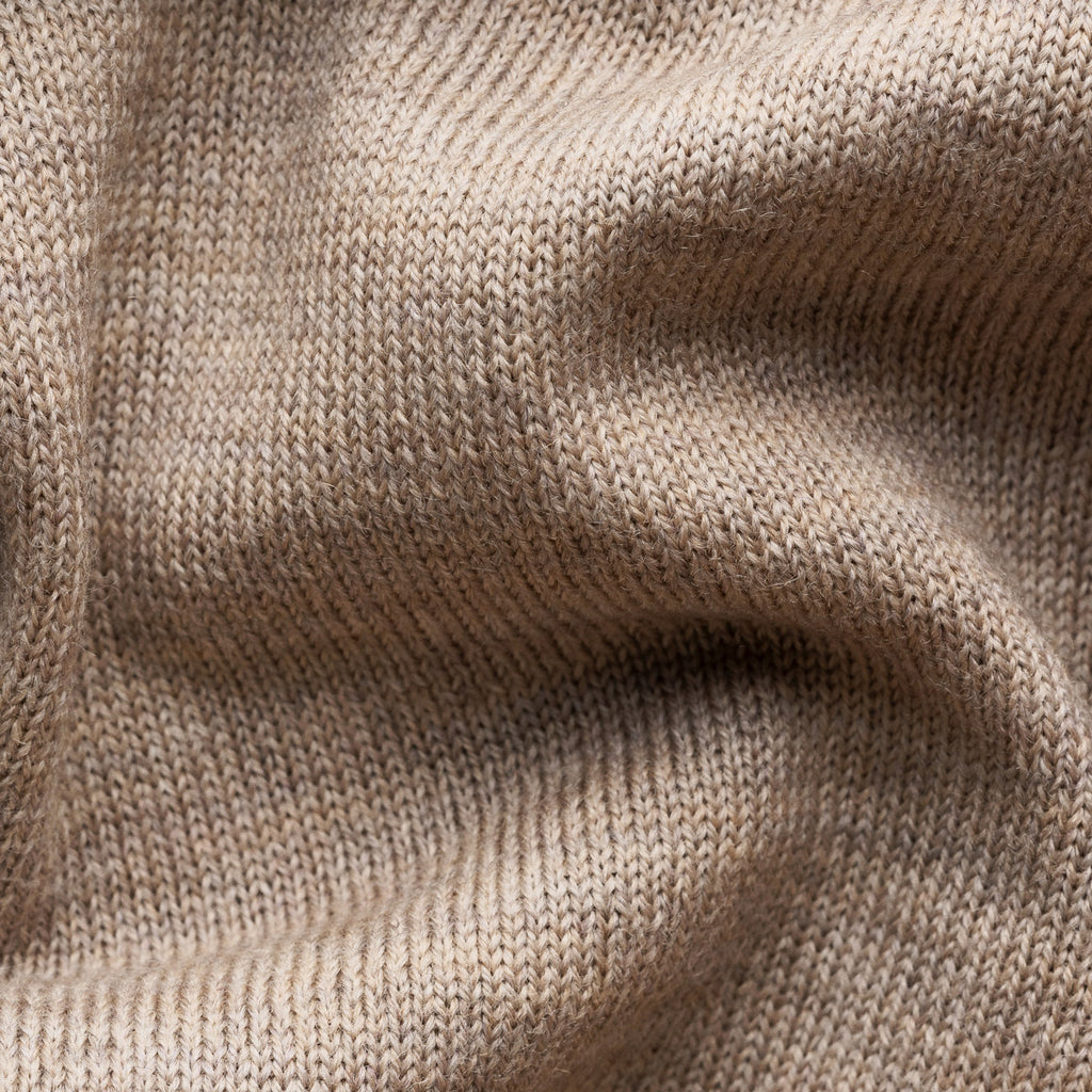 Close-up of a beige knit fabric texture with soft folds and ribbed stitching. Eton Cardigan available at Sakks Menswear in Southampton.