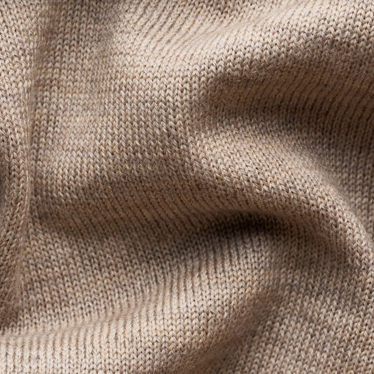 Close-up of a beige knit fabric texture with soft folds and ribbed stitching. Eton Cardigan available at Sakks Menswear in Southampton.