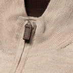 Close-up of a ribbed knit sweater in a light oatmeal beige colour, featuring a brown leather pull tab on the zipper. Eton Cardigan available at Sakks Menswear in Southampton.