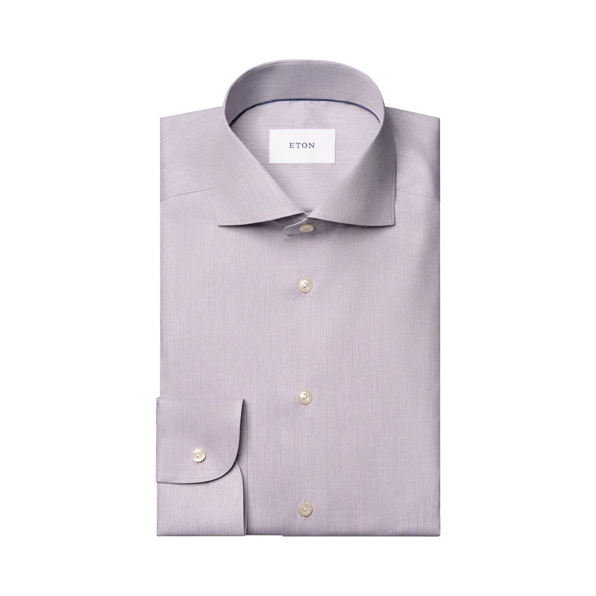 A light lavender dress shirt by ETON, neatly folded to show the collar, front buttons, and single-button cuff, on a solid white background. Eton Shirt available at Sakks Menswear in Southampton.