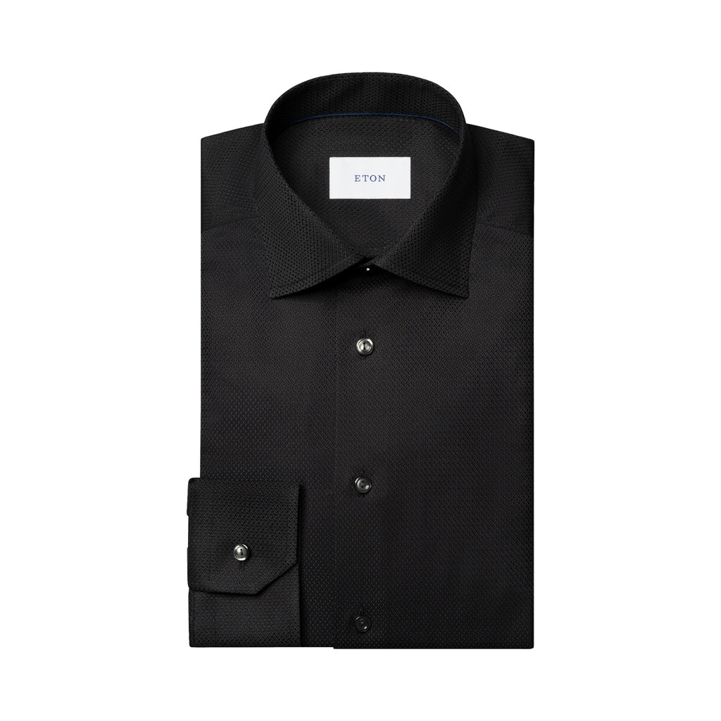 A folded black long-sleeve dress shirt with a subtle micro-texture pattern, featuring a pointed collar, button-down front, and a single-button cuff. The brand label 'ETON' is visible inside the collar. Eton Shirt available at Sakks Menswear in Southampton.
