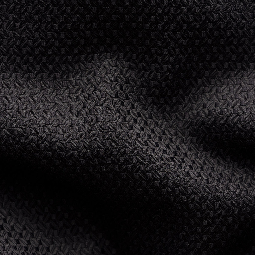 A close-up of a black textured fabric with a subtle woven geometric pattern and soft shadows across the surface. Eton Shirt available at Sakks Menswear in Southampton.