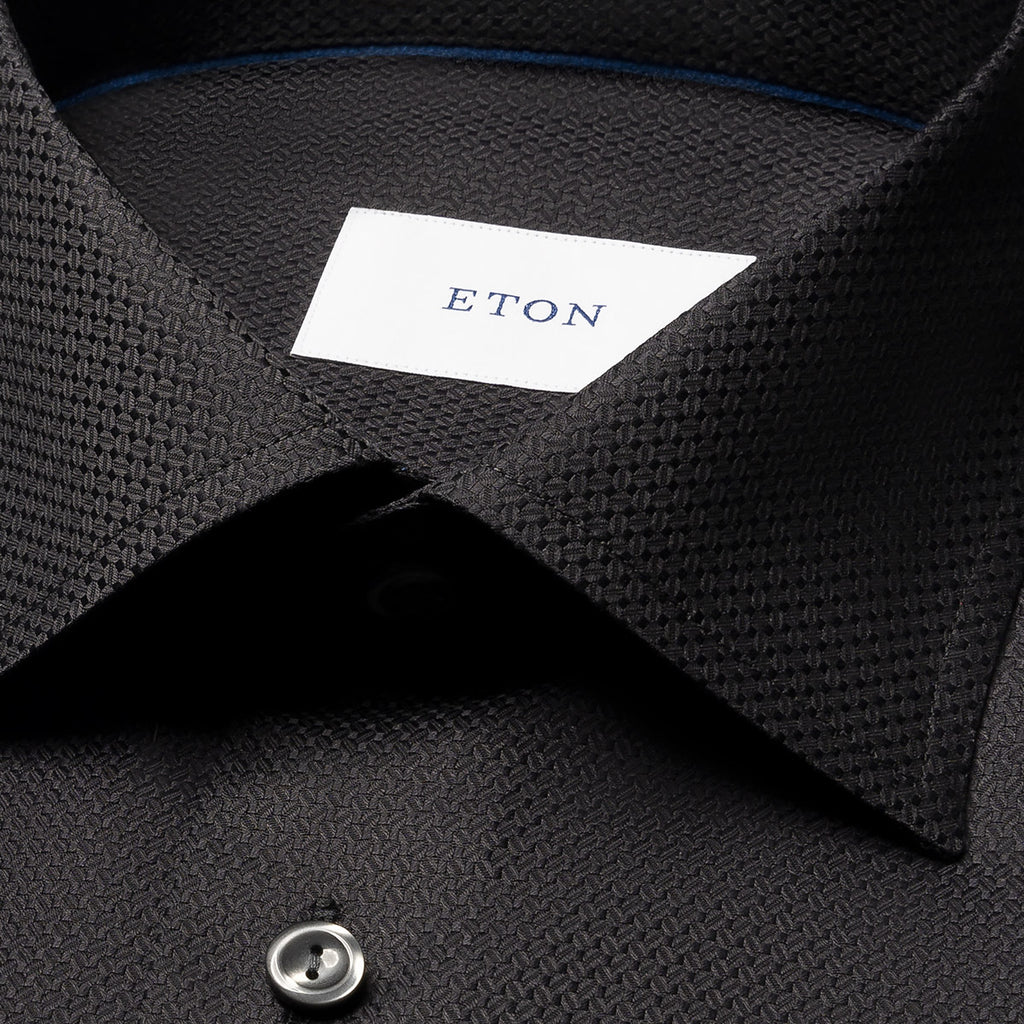 Close-up of a dark charcoal textured dress shirt collar with a white neck label reading ETON. Eton Shirt available at Sakks Menswear in Southampton.