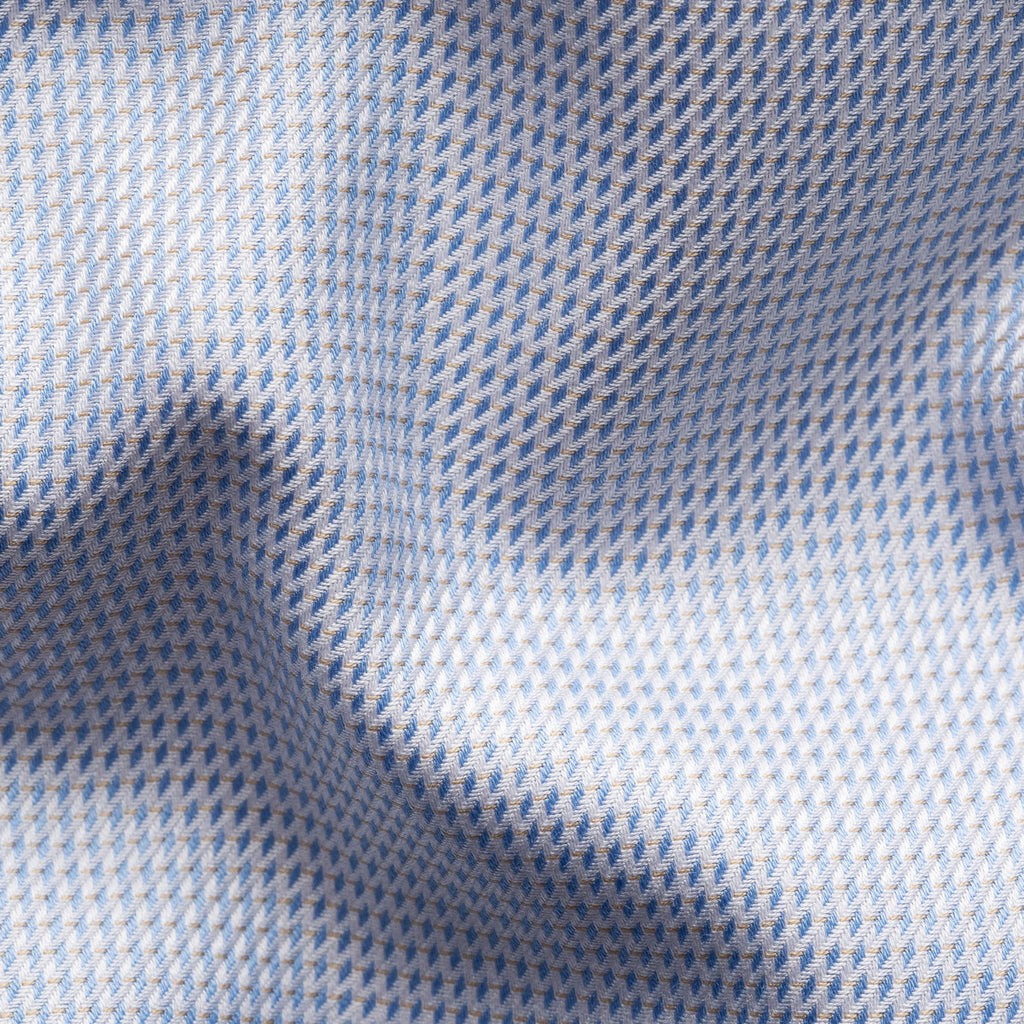 A close-up of a textured fabric with a fine blue and white houndstooth pattern, showing soft folds and shadows. Eton Shirt available at Sakks Menswear in Southampton.