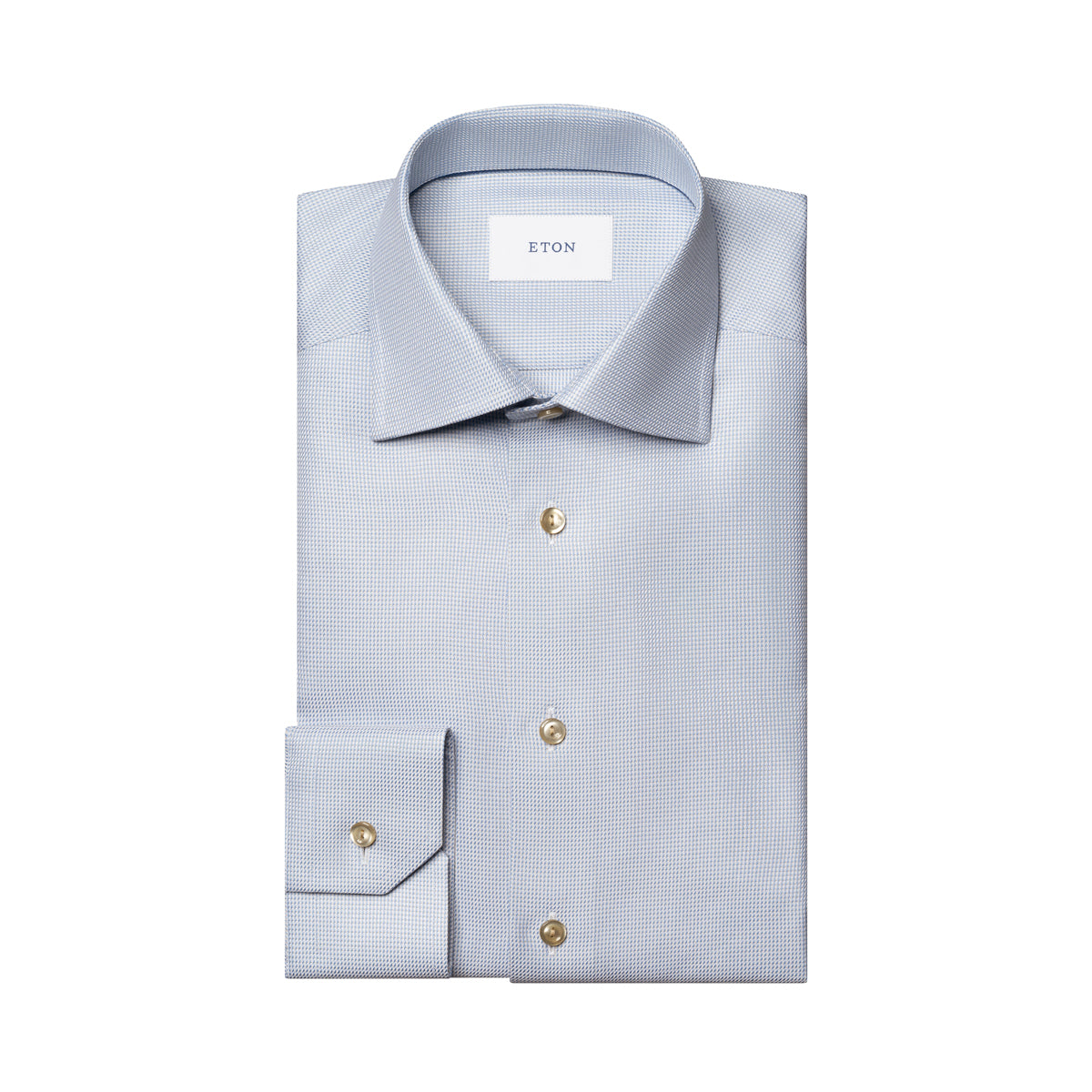 A folded light blue dress shirt with a subtle micro-check pattern, featuring gold buttons and a white neck label with the brand name ETON. Eton Shirt available at Sakks Menswear in Southampton.