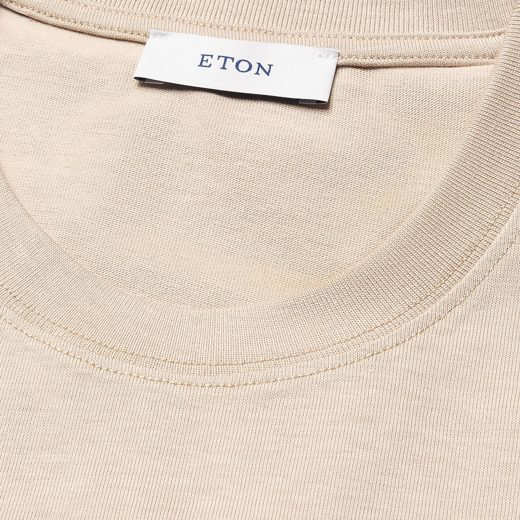Close-up of a cream-coloured ribbed knit garment, likely a t-shirt, showing the inner neck label with the brand name ETON. Eton T-Shirt available at Sakks Menswear in Southampton.
