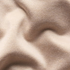 A close-up of draped beige fabric with a fine mesh or woven texture, showing soft folds and shadows. Eton Polo Available at Sakks Menswear in Southampton.