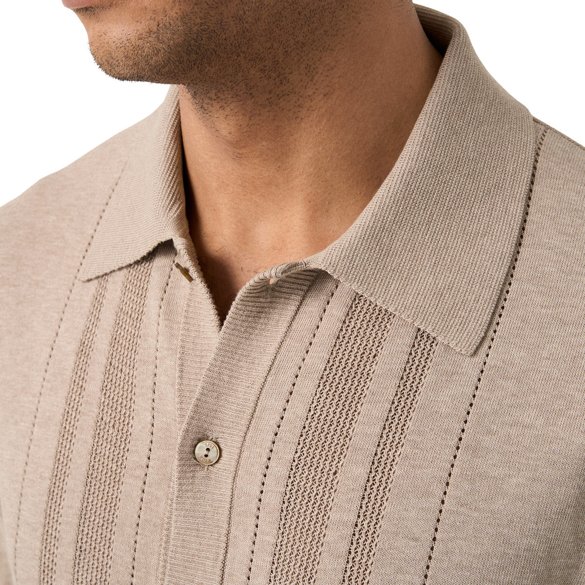 Close-up of a man wearing a beige ribbed knit polo shirt with vertical textured stripes and a buttoned collar. Eton Knitted Polo available at Sakks Menswear in Southampton.