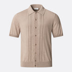 A beige short-sleeve knit polo shirt with vertical pleat details on the front, a button-down front, and a classic collar, shown against a light grey background. Eton Knitted Polo available at Sakks Menswear in Southampton.