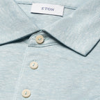 Close-up of a light blue textured collared shirt with cream buttons and a visible ETON neck label. Eton Polo. Sakks Menswear Southampton.