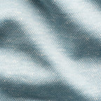 A close-up of textured fabric with a fine woven pattern in a light blue-gray color, showing soft folds and highlights. Eton Polo available at Sakks Menswear in Southampton.