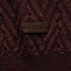 Close-up of a textured knit sweater in deep burgundy with a brown leather patch on the chest embossed with the brand name ETON. Eton Polo. Sakks Menswear Southampton.