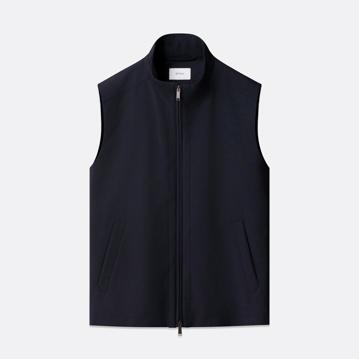A dark navy sleeveless zip-front vest with a stand collar and two vertical front pockets, shown flat against a light gray background. Eton Gilet. Sakks Menswear Southampton.