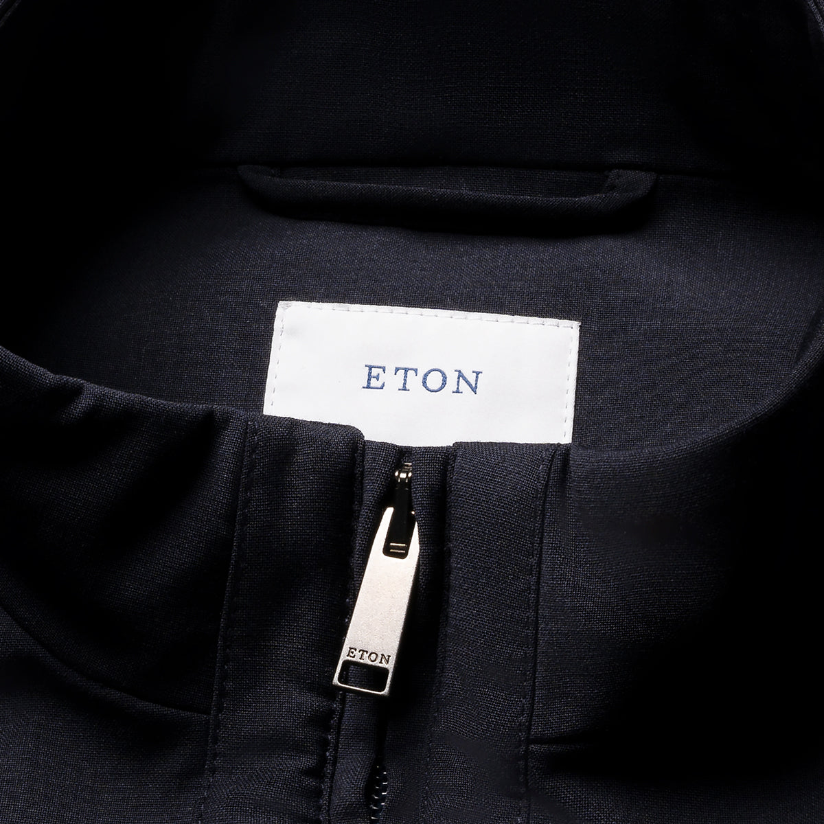 Close-up of a black zippered garment collar with a white rectangular ETON label and a silver zipper pull printed with ETON. Eton Gilet. Sakks Menswear Southampton.