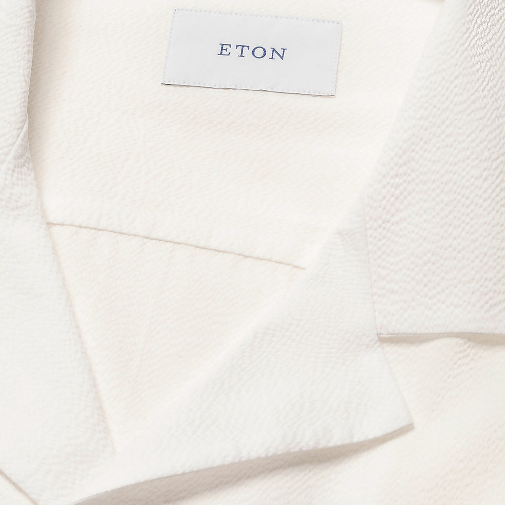 Close-up of a white textured fabric garment with a white brand label reading ETON. Eton Short Sleeve Shirt Sakks Menswear Southampton.