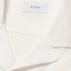 Close-up of a white textured fabric garment with a white brand label reading ETON. Eton Short Sleeve Shirt Sakks Menswear Southampton.