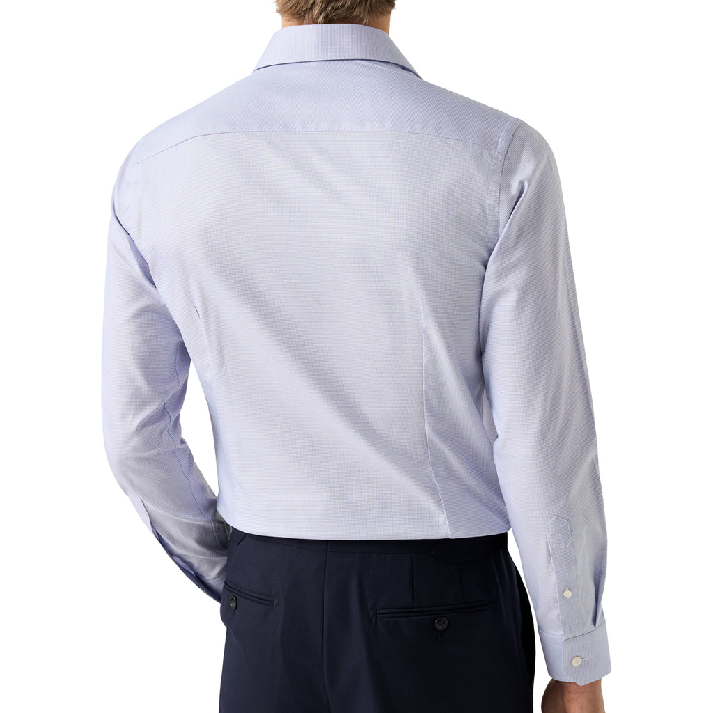 Rear view of a man wearing a light periwinkle blue long-sleeve dress shirt and dark trousers against a white background. Eton Shirt. Sakks Menswear Southampton.
