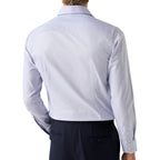Rear view of a man wearing a light periwinkle blue long-sleeve dress shirt and dark trousers against a white background. Eton Shirt. Sakks Menswear Southampton.