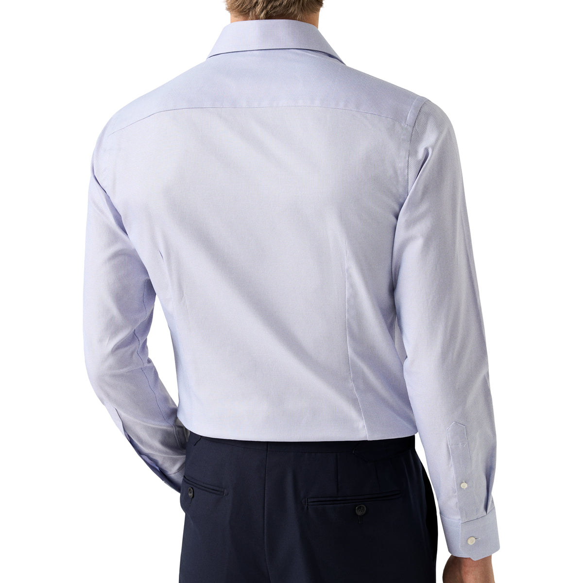 Rear view of a man wearing a light periwinkle blue long-sleeve dress shirt and dark trousers against a white background. Eton Shirt. Sakks Menswear Southampton.