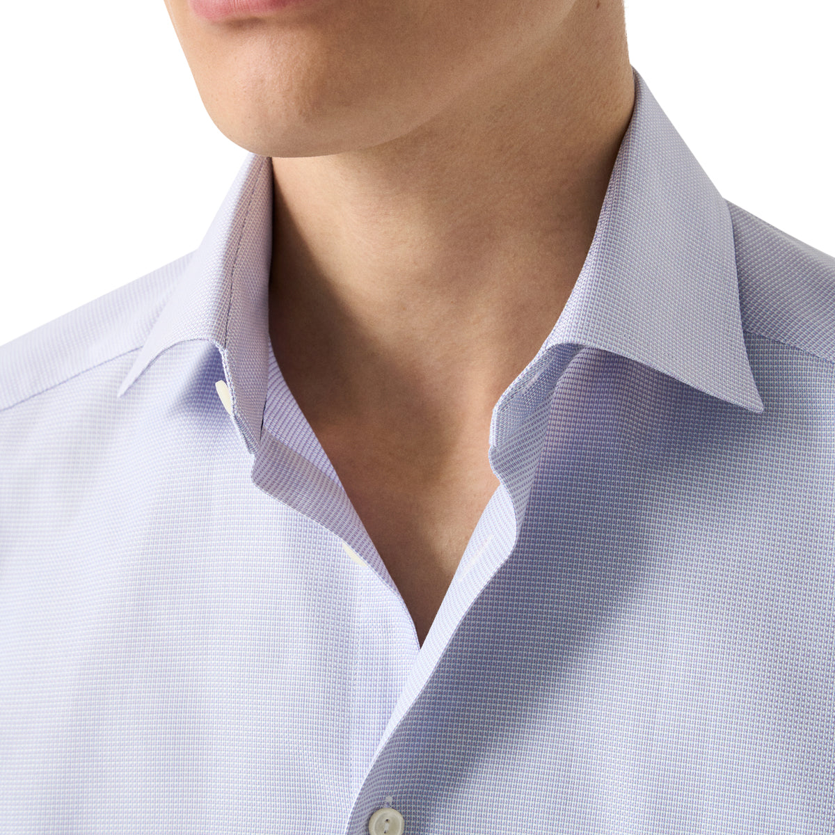 Close-up of a man wearing a light blue and white micro-check patterned dress shirt, showing the collar and chest area. Eton Shirt. Sakks Menswear Southampton.