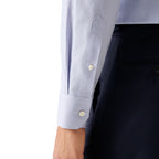 Close-up of a light blue and white micro-check patterned dress shirt cuff with white buttons, worn with dark navy trousers. Eton Shirt. Sakks Menswear Southampton.