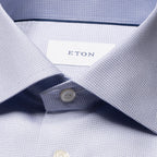Close-up of a light blue and white micro-check patterned dress shirt collar with a white button and an ETON brand label. Eton Shirt. Sakks Menswear Southampton.