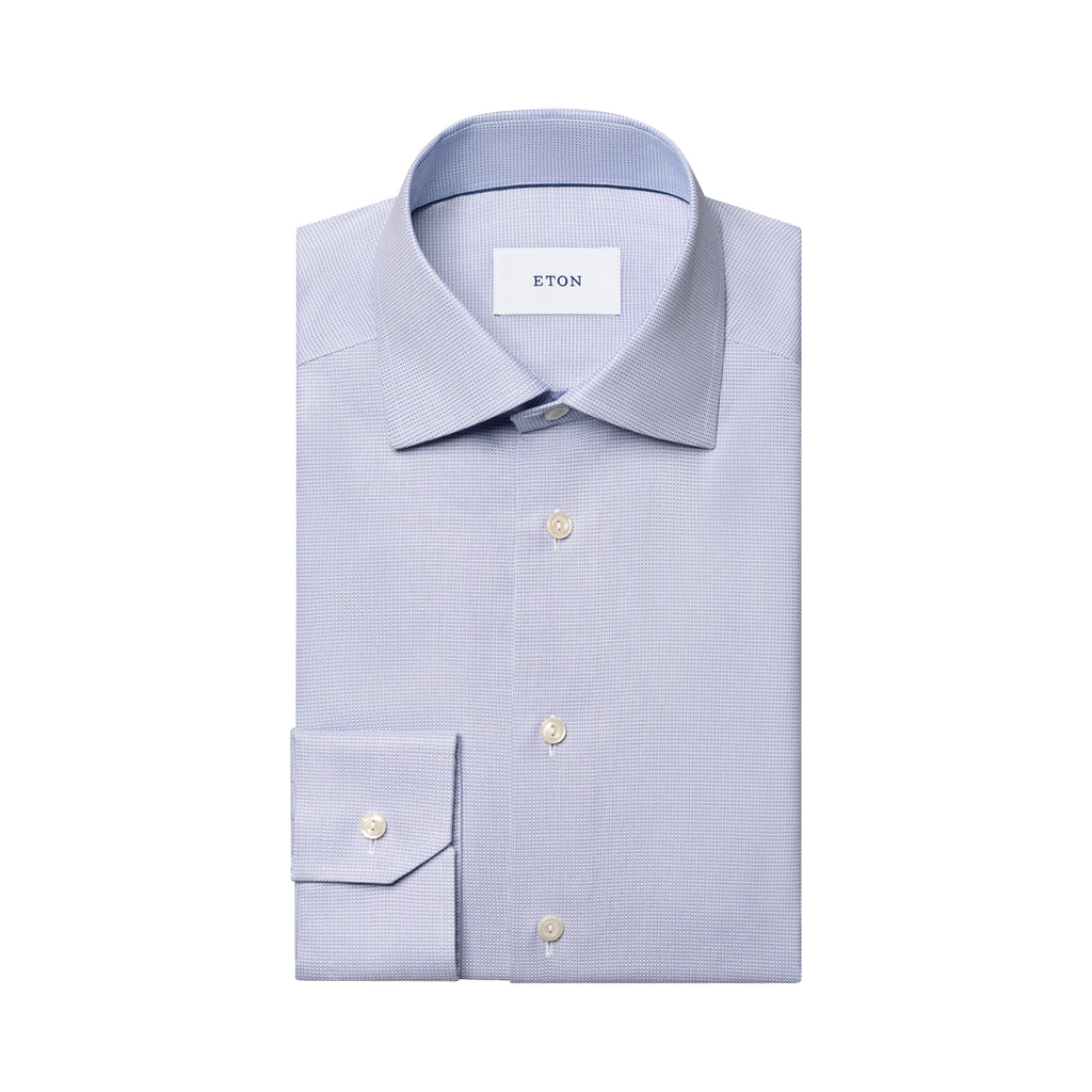 A light blue and white micro-check patterned dress shirt by ETON, neatly folded with a spread collar and a single cuff, shown on a solid white background. Eton Shirt. Sakks Menswear Southampton.