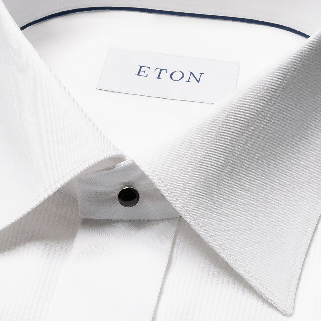 Close-up of a white dress shirt collar with a visible ETON neck label and a single black button. Eton Dinner Shirt. Sakks Menswear Southampton.