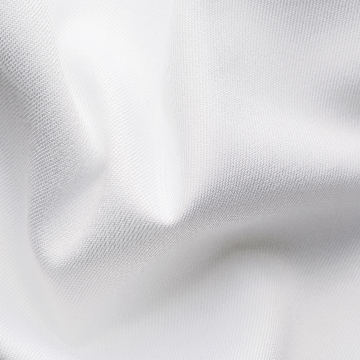 A close-up of white fabric with soft folds and a fine woven texture filling the frame. Eton Dinner Shirt. Sakks Menswear Southampton.