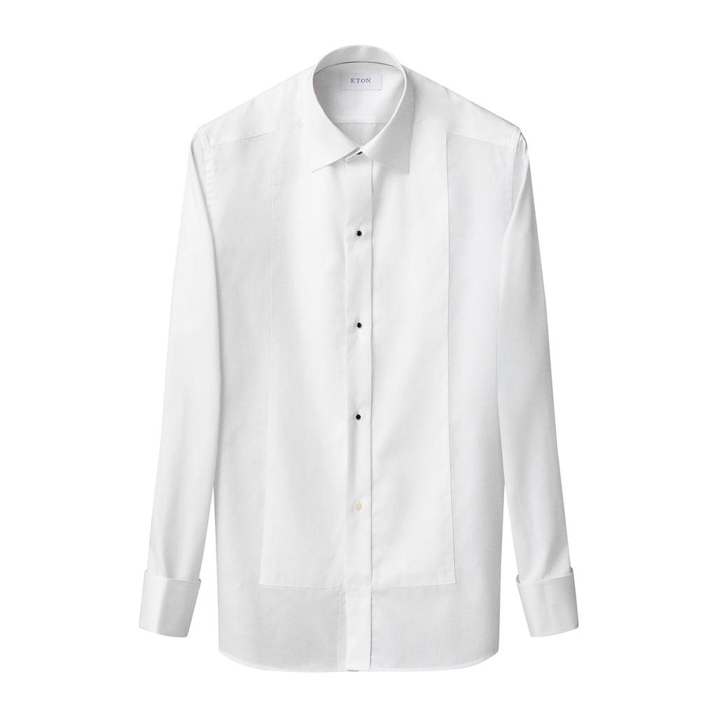 A white long-sleeve button-up shirt with a pointed collar, black buttons, and front pleat details, shown on a plain white background. Eton Dinner Shirt. Sakks Menswear Southampton.