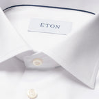 Close-up of a white dress shirt collar with a visible ETON neck label and white buttons, photographed on a clean white background. Eton Shirt. Sakks Menswear Southampton.