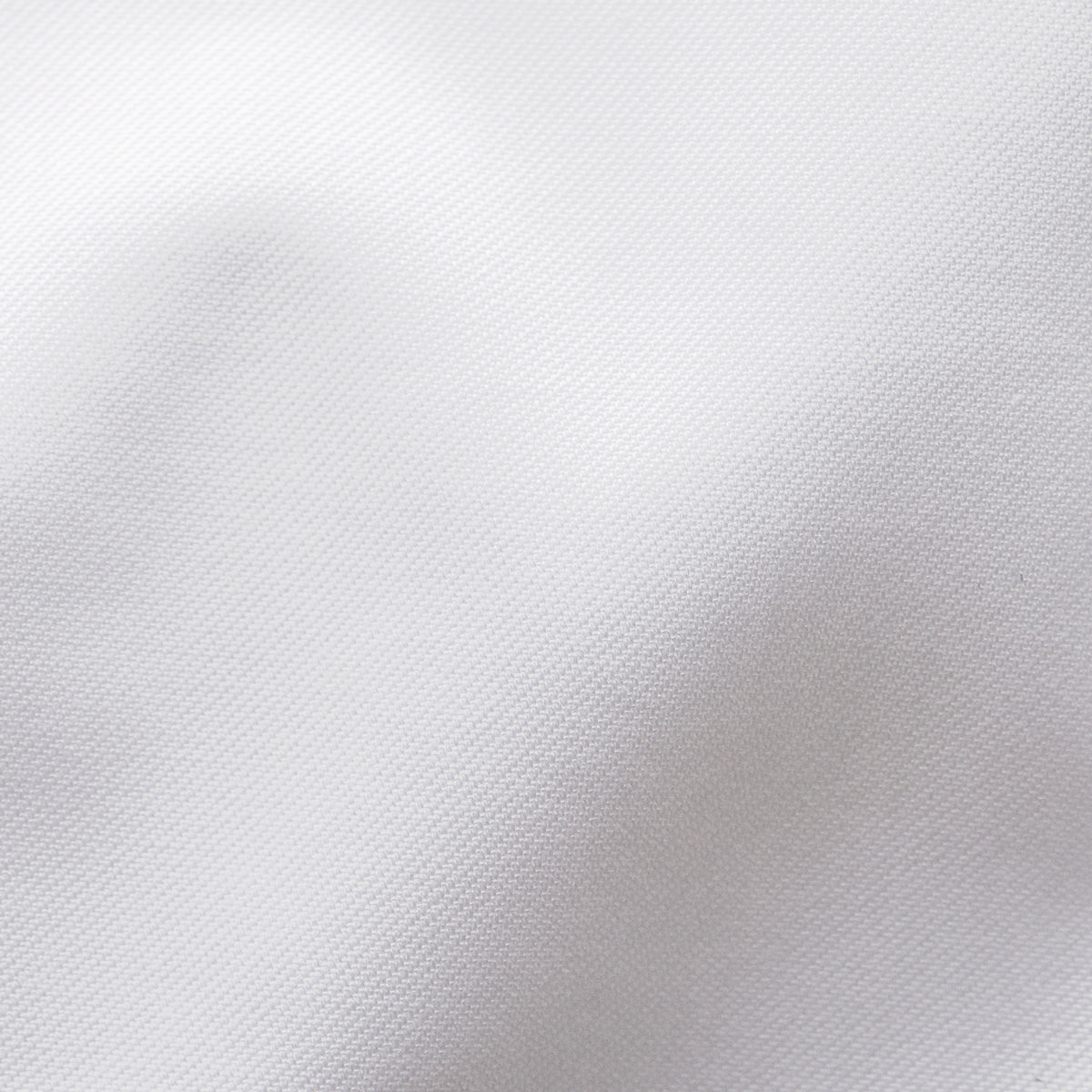 A close-up of white textured fabric with soft folds and a fine woven pattern. Eton Shirt. Sakks Menswear Southampton.
