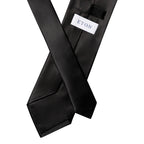 A black satin necktie with a white rectangular label reading 'ETON' in navy blue, shown crossed over itself on a plain white background. Eton Ties available at Sakks Menswear in Southampton.