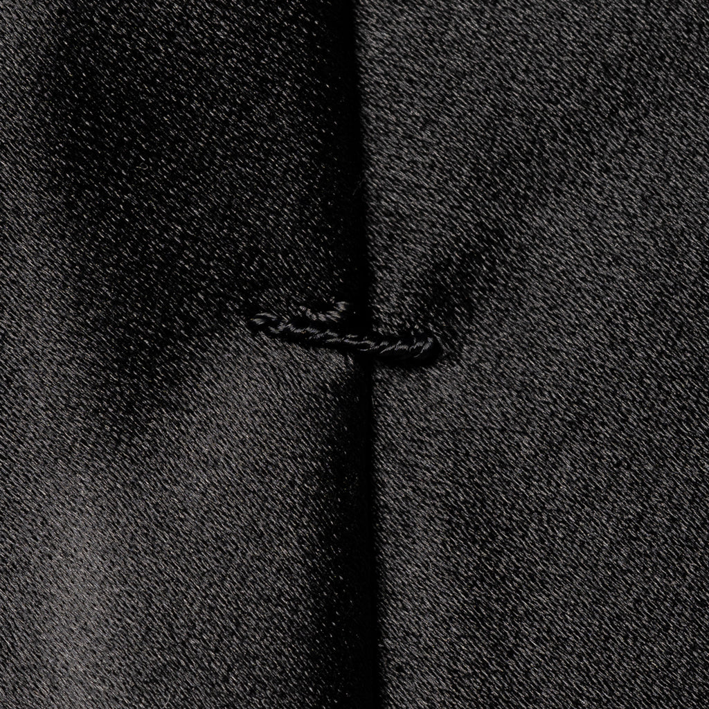 Close-up of a black textured fabric with a central vertical seam and a small stitched detail near the middle. Eton Ties available at Sakks Menswear in Southampton.