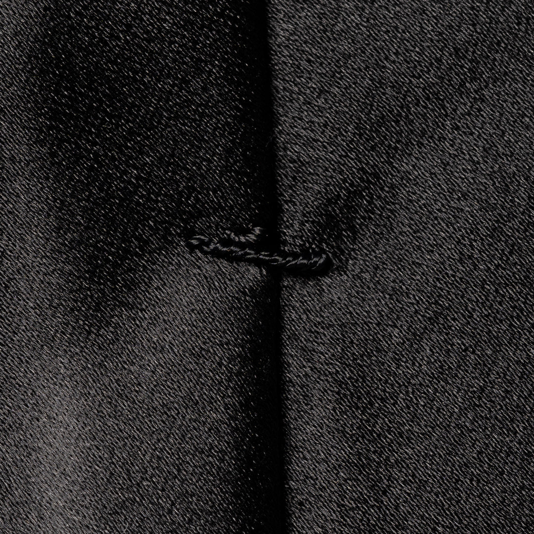 Close-up of a black textured fabric with a central vertical seam and a small stitched detail near the middle. Eton Ties available at Sakks Menswear in Southampton.