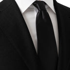 A classic black necktie neatly knotted and styled with a white dress shirt and a black suit jacket. Eton Ties available at Sakks Menswear in Southampton.