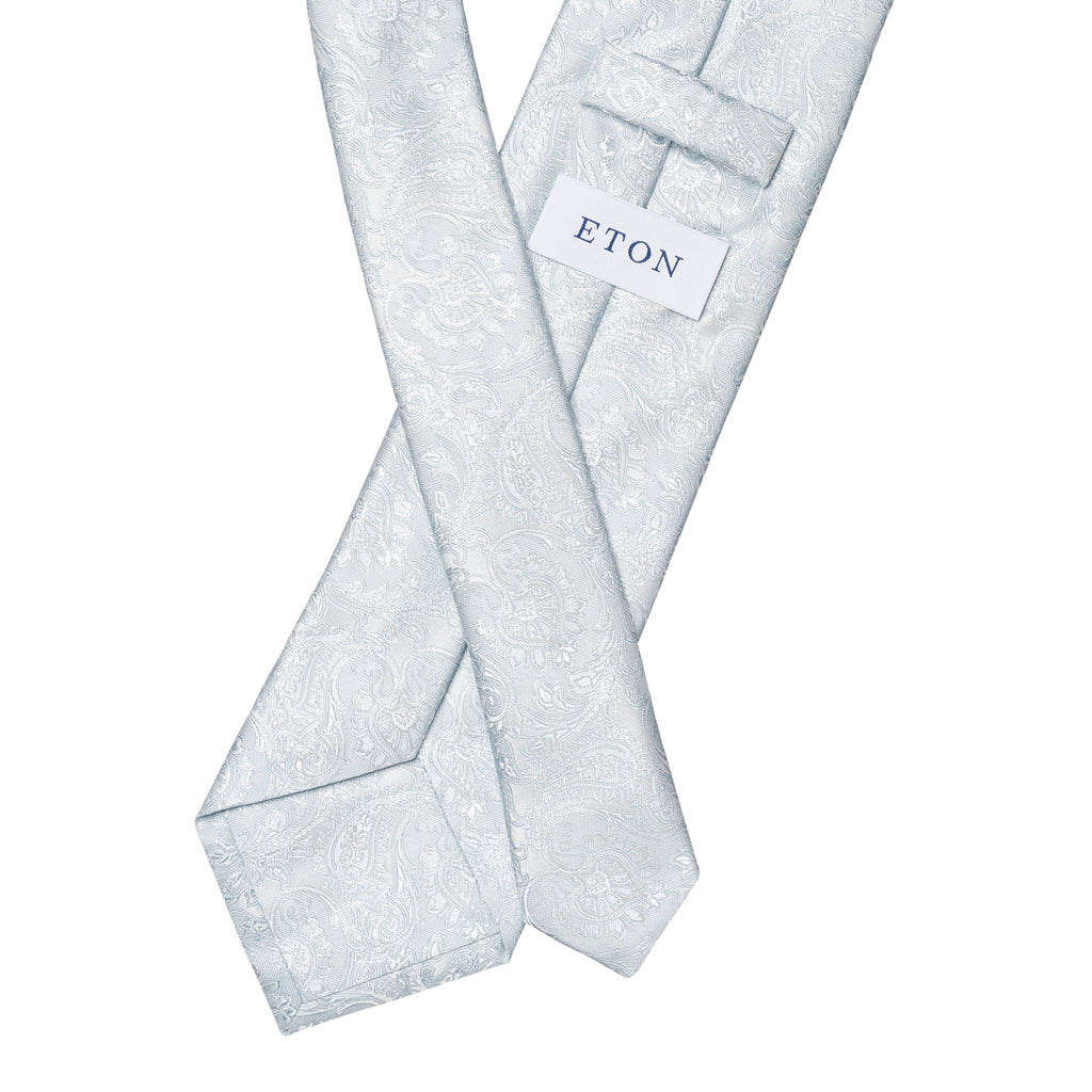 A light blue paisley patterned necktie with a white brand label reading 'ETON', displayed against a solid white background. Eton Ties available at Sakks Menswear in Southampton.