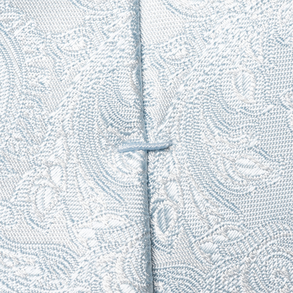 Close-up of a light blue and white patterned fabric with a central vertical seam and a small button closure. Eton Ties available at Sakks Menswear in Southampton.