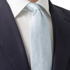 A light blue paisley patterned silk necktie, knotted and styled with a white dress shirt and a dark navy suit jacket. Eton Ties available at Sakks Menswear in Southampton.