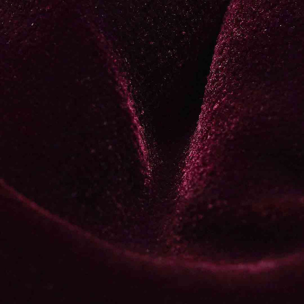 A close-up of dark plum velvet fabric with a soft sheen and visible fine texture. Eton Bow Tie available at Sakks Menswear in Southampton.
