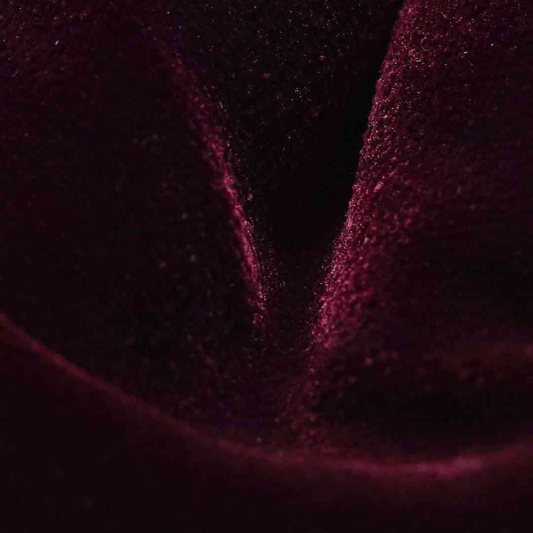 A close-up of dark plum velvet fabric with a soft sheen and visible fine texture. Eton Bow Tie available at Sakks Menswear in Southampton.