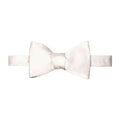 A pre-tied bow tie in a warm ivory or cream satin fabric, shown flat against a solid white background. Eton Bow Ties available at Sakks Menswear in Southampton.