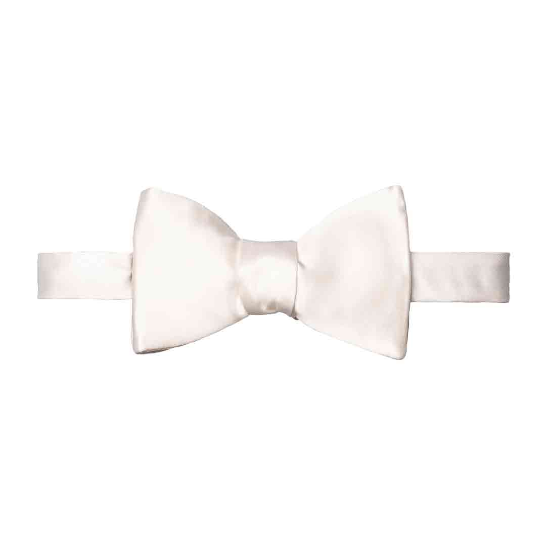 A pre-tied bow tie in a warm ivory or cream satin fabric, shown flat against a solid white background. Eton Bow Ties available at Sakks Menswear in Southampton.